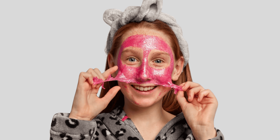 Niña aplicando una mascarilla peel-off brillante, sonriendo